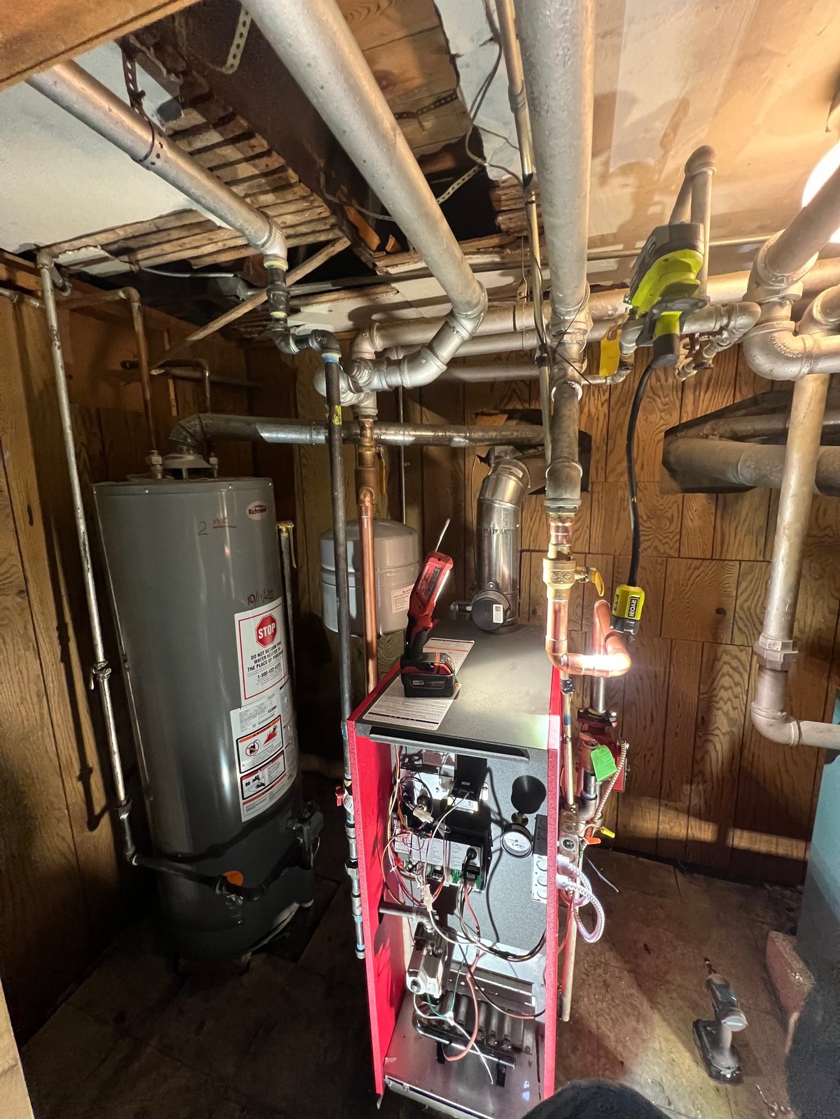 Technician holding manifold gauges with blue and red pressure dials connected to HVAC equipment